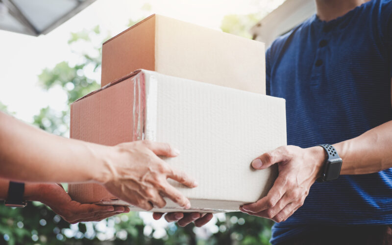 Home delivery service and working service mind, Woman customer hand receiving a cardboard boxes parcel from delivery service courier.