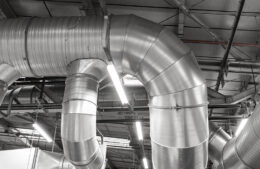 Part of industrial crane with metal hook passing large panel or solar battery from one place to another in modern factory