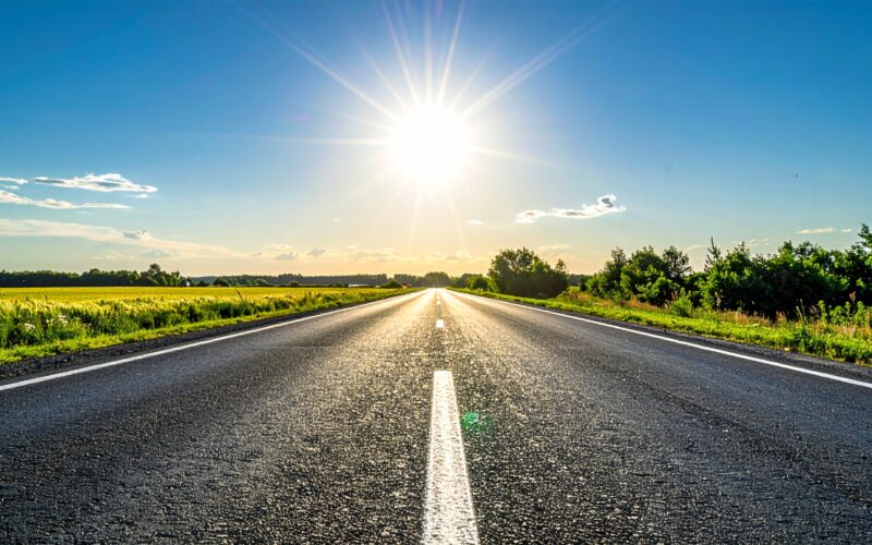 アスファルトの道路と炎天下の青空が広がる夏の風景