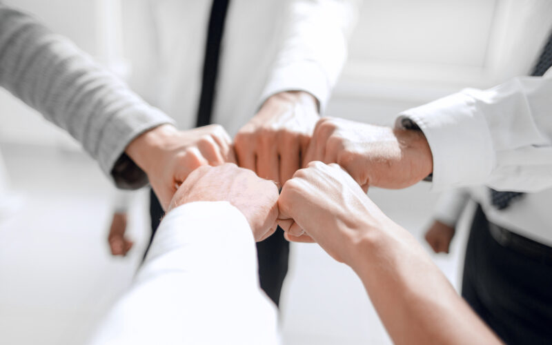 Close up of young businessman and businesswoman making a fist bump on building background